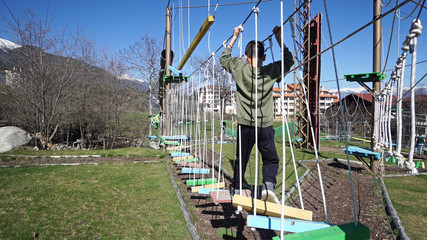 young boy passing the cable route, extreme sport in adventure park