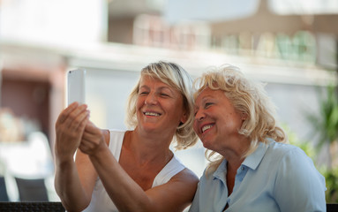 Two smiling middle-aged women making a selfie with a smartphone