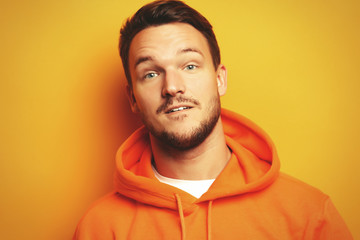 Portrait of a smart young man wearing casual standing against yellow background