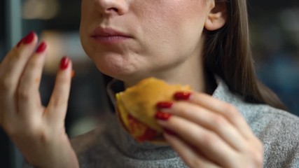 Caucasian woman eating hamburger in a cafe