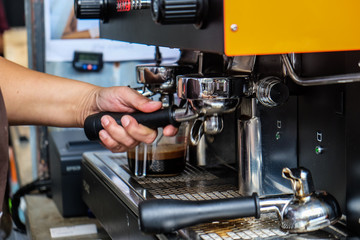 Espresso pouring machine with barista hand close up