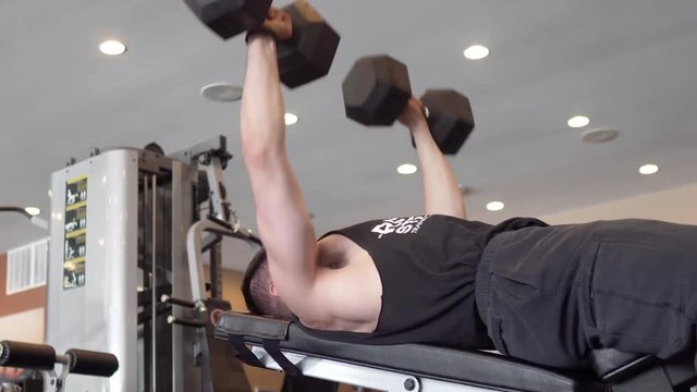 Person lifting weights and exercising in the gym. Pan to the right. 24 fps. Shot in 4k exported in 1080p. Shallow depth of field.