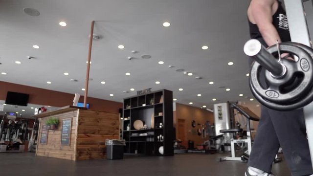 Person lifting weights and exercising in the gym. 4K. 24 fps. Shallow depth of field.