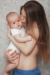 A calm full newborn baby - in his young naked mothers arms