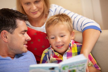 Obraz premium A boy and his parents sitting together and reading a book