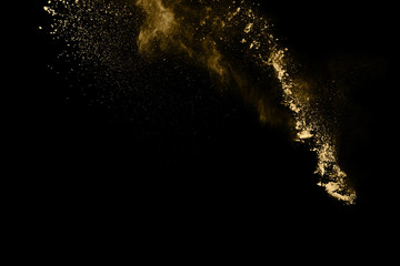 Fototapeta na wymiar Golden powder explosion on black background. Freeze motion.