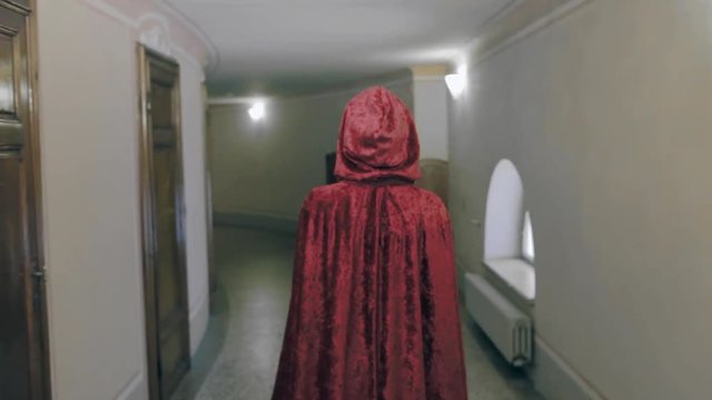 Mysterious woman with a red cloak walks in a corridor