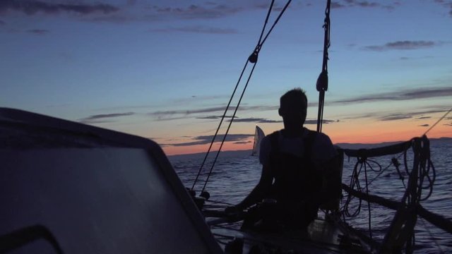 lonely man helm sailing boat in the sunset with a cinematic light