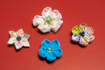 Japanese kanzashi hand made flowers constructed from kimono material  on a red background
