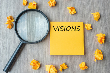 vision words on yellow note with crumbled paper and magnifying glass on wooden table background. SEO, Idea, goal, Strategy, Analysis, Keyword and Content concept