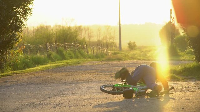 child for the first time on a bike fall down in a beautiful light at sunset in the countryside