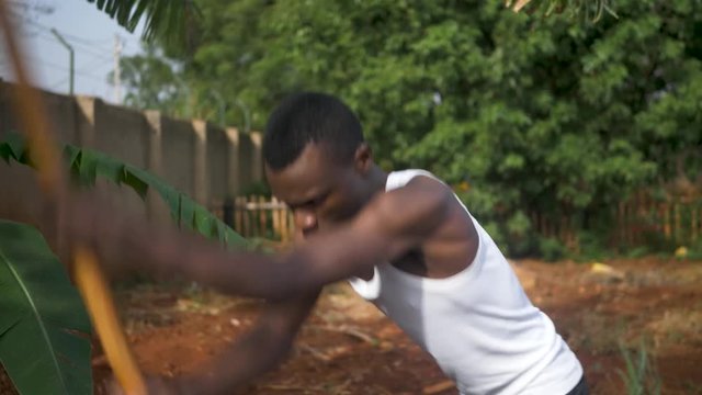 A close shot of an African man digging in his garden using a hoe in the hot sun in rural Africa.