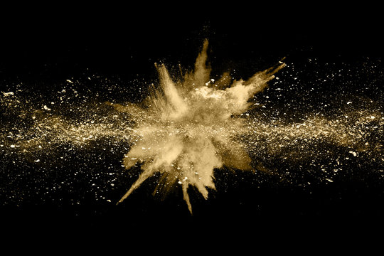 Golden powder explosion on black background. Freeze motion.