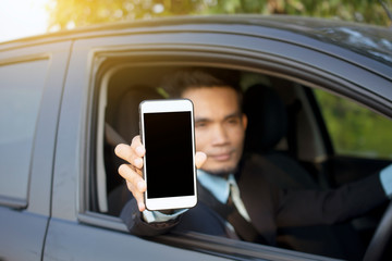 Businessman sitting in car holding mobile smart phone