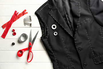 Unfinished jacket with tailor's accessories on white table