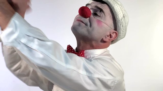 Emoji clown - Disappointed and Expressionless Face. A clown throws a cartoon-styled heart to the air to indicate that love is over. His face displays of &lsquo;no comment&rsquo;. (Closeup shot size)