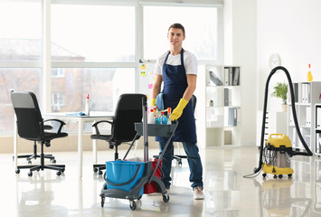 Male janitor with trolley in office