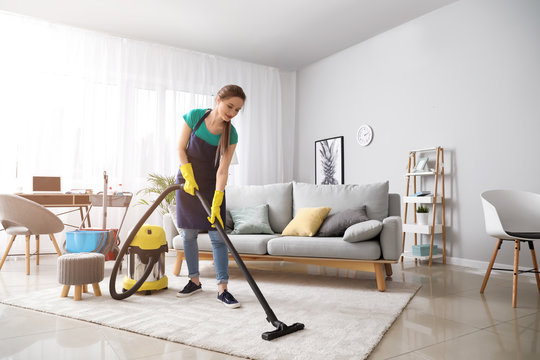 Female janitor with vacuum cleaner in room