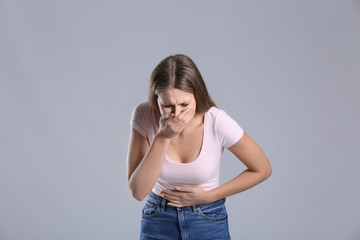 Pregnant woman suffering from toxicosis on grey background