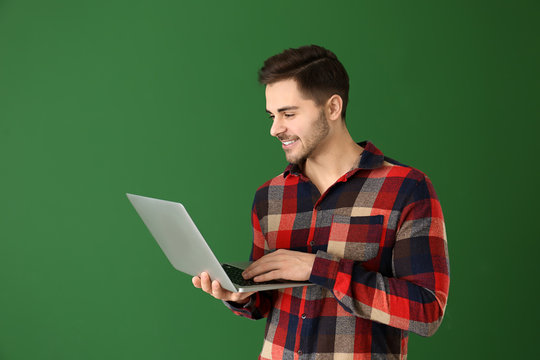 Male programmer with laptop on color background