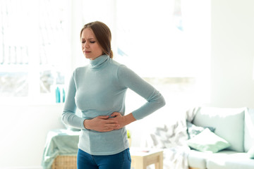 Young woman suffering from stomachache at home