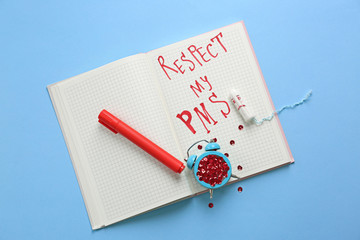 Notebook with text RESPECT MY PMS, clock and tampon on color background