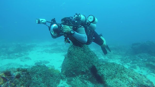 A slow-motion video of an underwater cameraman taking photos in the ocean of marine life with underwater equipment with a flash