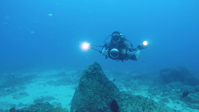 A video of an underwater cameraman filming marine life in the ocean with underwater equipment and lights