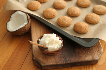 Coconut oil with tasty cookies on wooden table