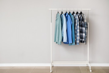Rack with stylish clothes near grey wall