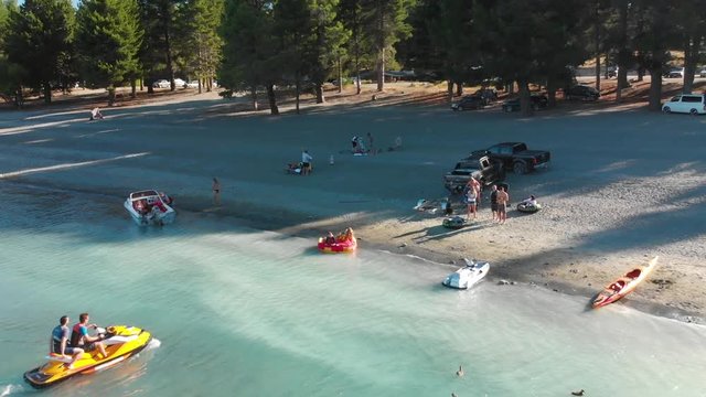 SLOWMO - Jet Ski arriving to rocky beach with Beautiful Turquoise Blue Water - Lake Tekapo, New Zealand - Aerial