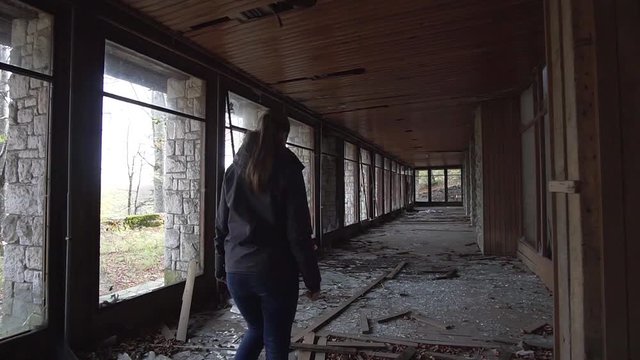 Girl walks through mysterious ruins of abandoned mansion
