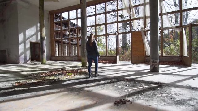 Young woman walking in abandoned mansion, urban exploration tracking shot