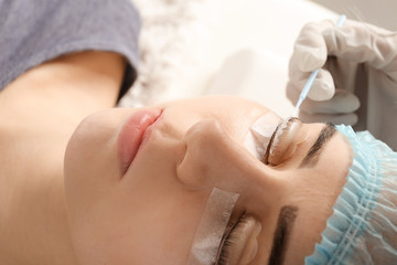 Obraz na płótnie Canvas Young woman undergoing procedure of eyelashes lamination in beauty salon
