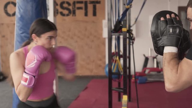 Young beautiful women work out with kick boxing and punching the partner with a pick gloves.
Practice session with a concept of sport and fitness .