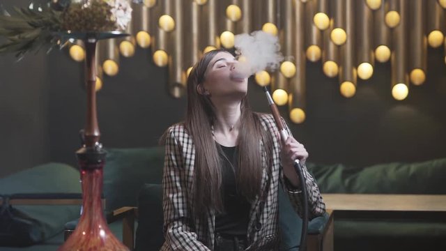 Brunette woman enjoying smoking shisha out of a hookah