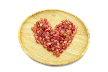 Fresh pomegranate heart shape on wooden plate isolated on white background