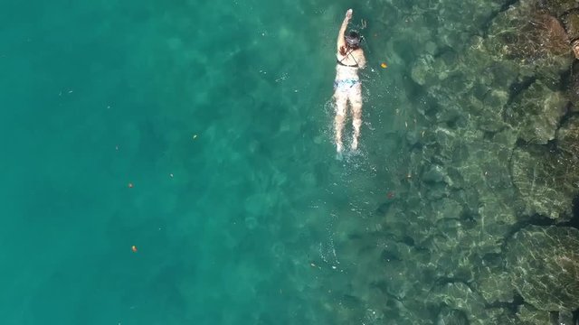 A female snorkeler in a bathing costume swimming along in the ocean