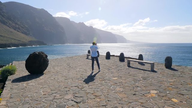 View of a tourist shooting the cliffs of Los Gigantes, Tenerife (Canary Islands) against sunlight