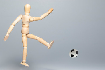 Football player kicks the ball. Abstract image with a wooden puppet