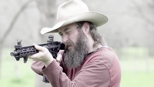 Faded vintage look of a cowboy taking aim of a target on his property, ready to fire the weapon, slow motion 23.98 fps.