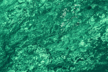 Vintage green background. Rough painted wall of emerald color. Imperfect plane of virid colored. Uneven old decorative toned backdrop of green tint. Texture of emerald hue. Ornamental stony surface.