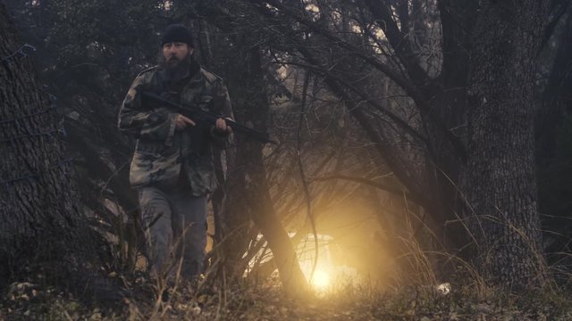 Ground view of a male hunter wearing camo, walking in the woods while looking for wildlife, slow motion 23.98 fps.