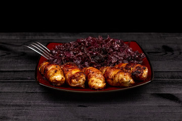 Fried homemade grilled sausages or chevapchichi with stewed sauerkraut on a wooden rustic background