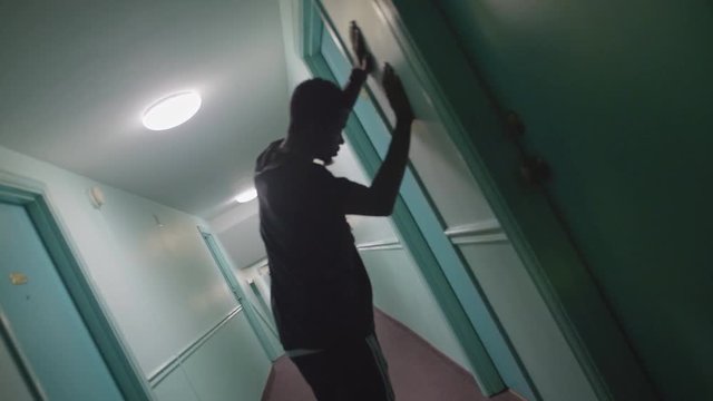 African American male stumbling into a wall in a hallway