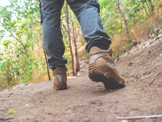Hiking man with trekking boots walking on the trail in forest