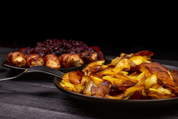 Fried homemade grilled sausages or chevapchichi with stewed sauerkraut on a wooden rustic background