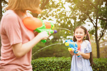 mother and little girls playing water guns in the park