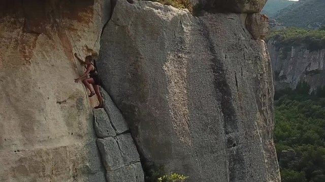 dramatic drone footage of a female rock climber figuring out the next moves on route.rocky mountain. Beauduc Frankreich. filmed with drone 1080p