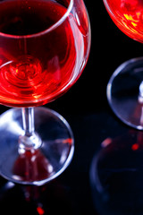 Two Glasses of red wine in night club on black background with reflection. Vertical image.